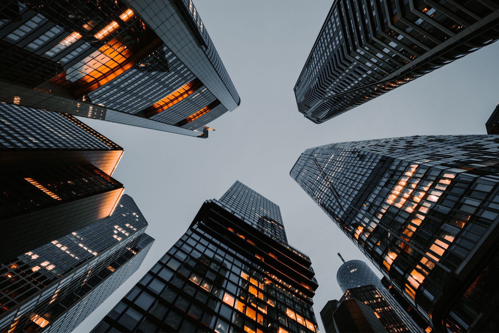 Low-angle view of modern glass office towers at dusk.